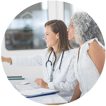 Two women, a doctor and patient, reviewing information on a computer screen.
