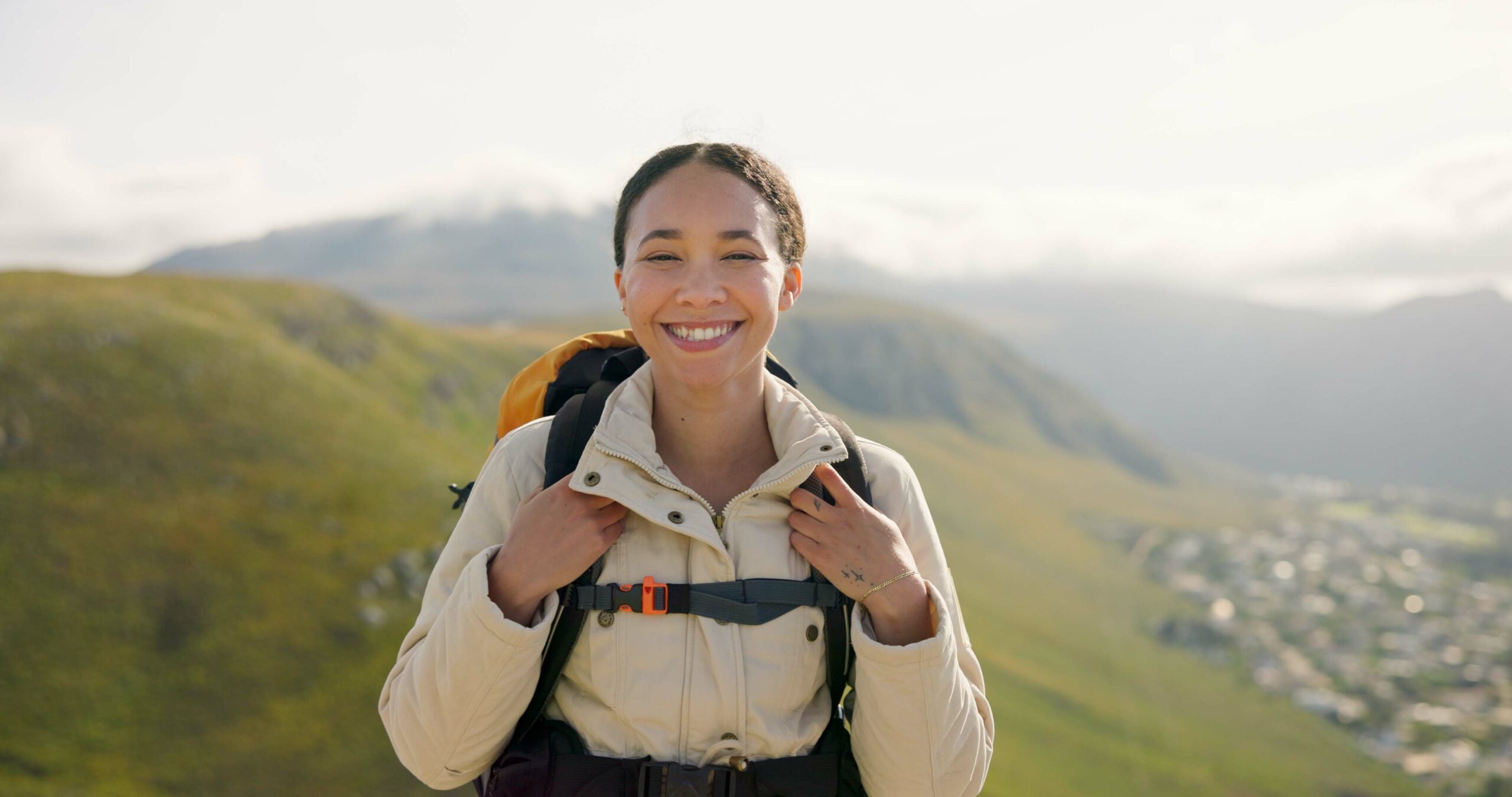 Happy woman, face and backpack with mountain for hiking, adventure or outdoor journey in nature. Po.